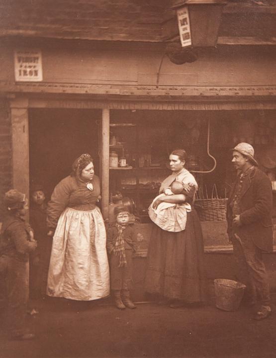 A family stands outside a shop after a flooding in Lambeth. The hard-hitting scenes of widespread poverty seem like a scene from Charles Dickens novel. (SWNS)